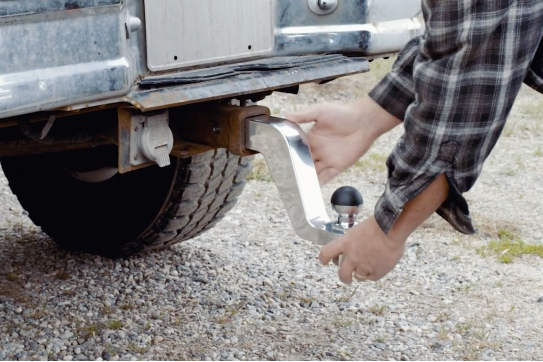Andersen Hitches Alumistinger on the back of a pickup truck. A man is securing the Alumistinger in place into the receiver. 