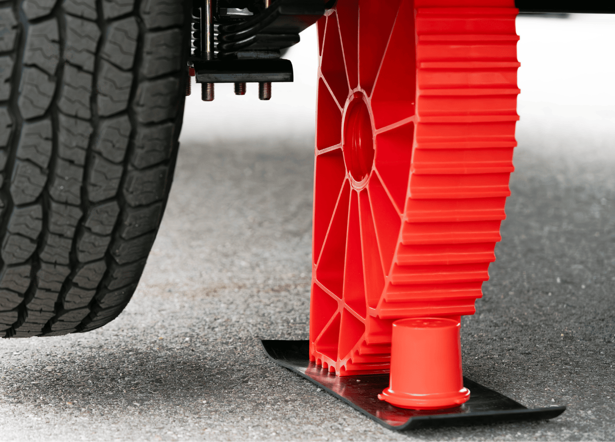 Showing the Andersen Single Axle Rapid Jack (S.A.R.J) in the upright position holding up a tire off the ground. View from the backside showing the chock holding up the SARJ for added safety and security,